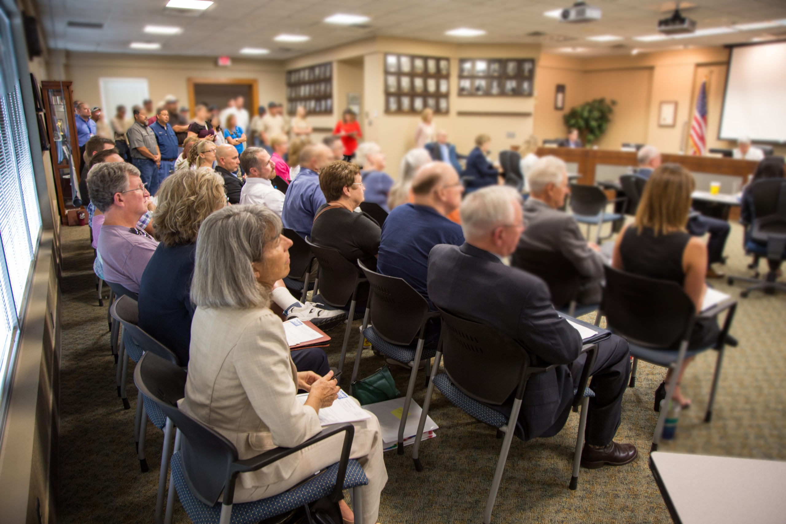 Board meeting with attendees looking on.